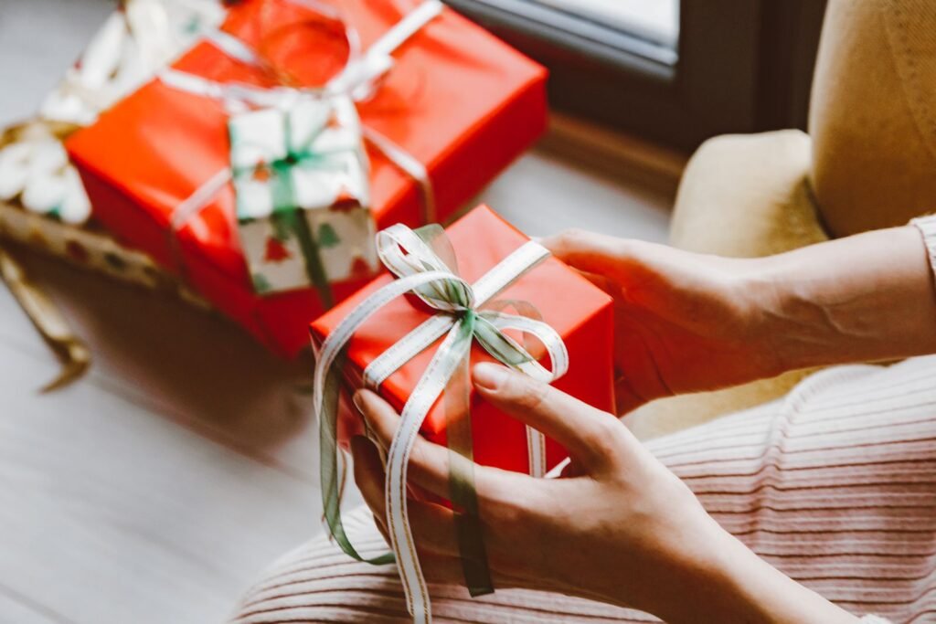 Mains qui tiennent un cadeau emballé avec un ruban