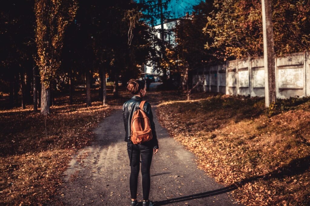 Femme qui marche seule sur un chemin bordé de feuilles en automne