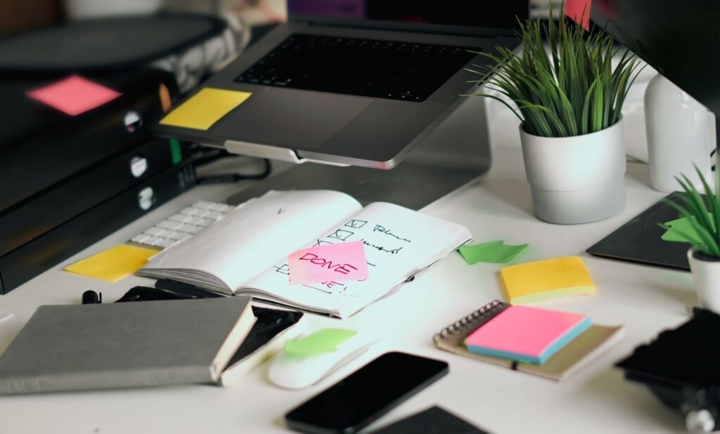Bureau encombré avec ordinateur portable, carnets et notes autocollantes colorées