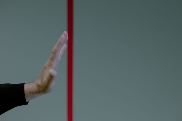Main faisant un geste d'arrêt devant une ligne rouge, symbole de limite