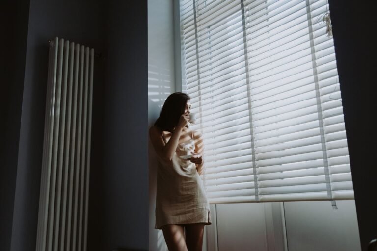 Femme dans la lumière du matin près d'une fenêtre, tasse à la main