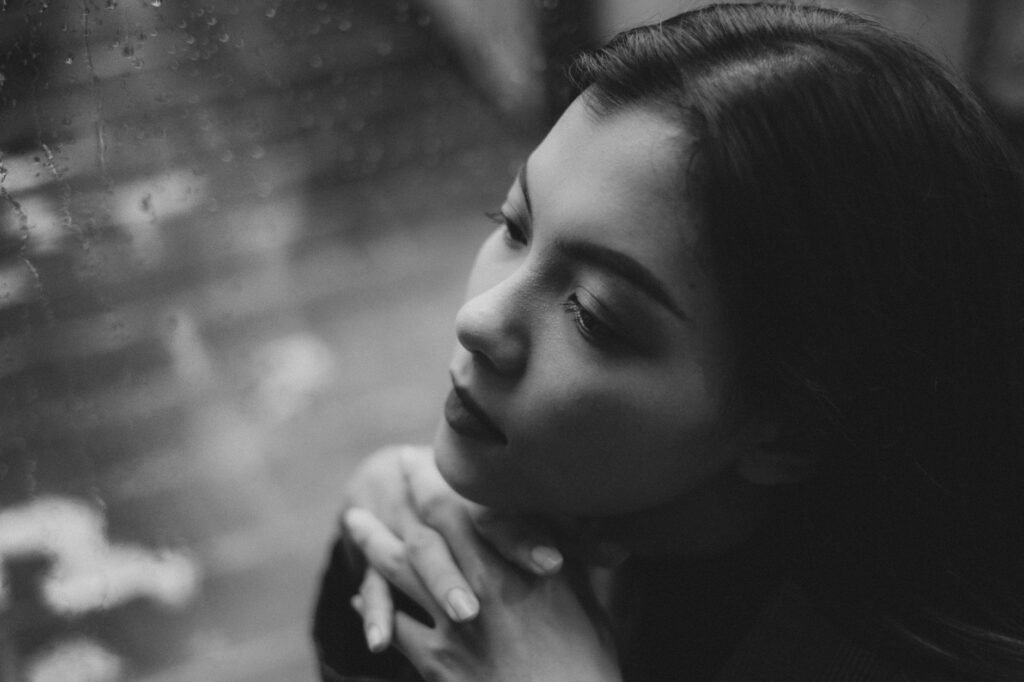 Femme pensive devant une fenetre un jour de pluie