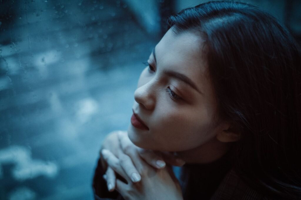 Femme pensive derrière une fenêtre un jour de pluie